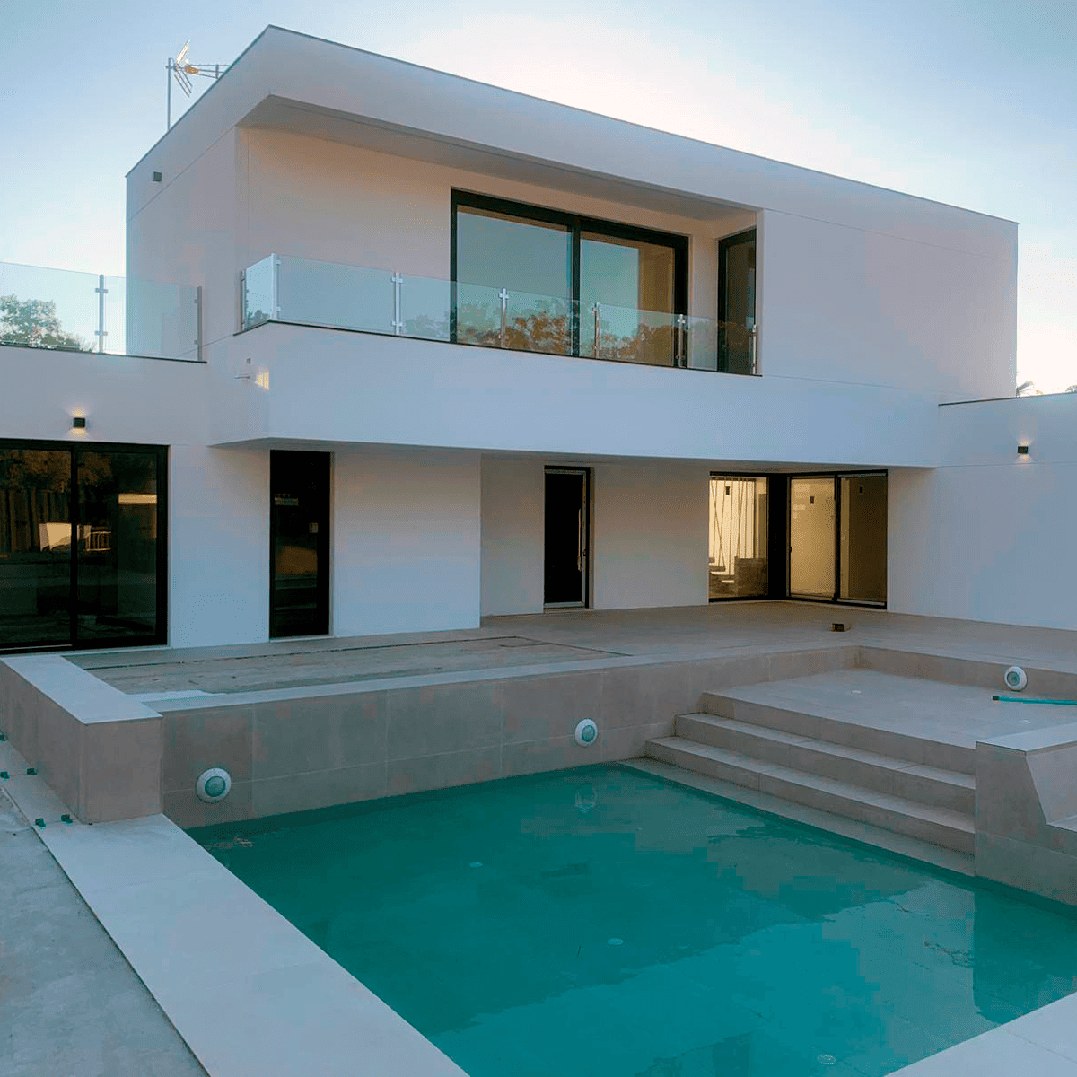 Proyecto de vivienda unifamiliar de estilo minimalista diseñado por arquitecto en Huelva, con fachada blanca, grandes ventanales y piscina de diseño.